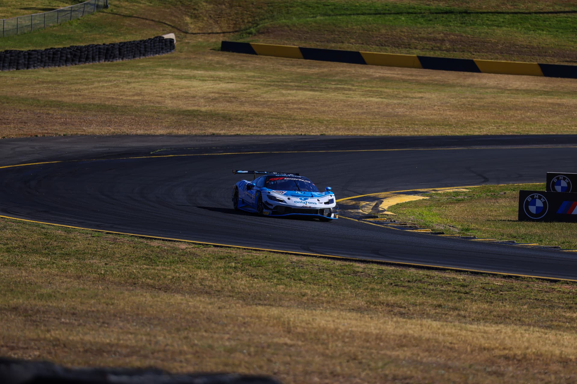 Blue and white GT car rounding a broad circuit bend