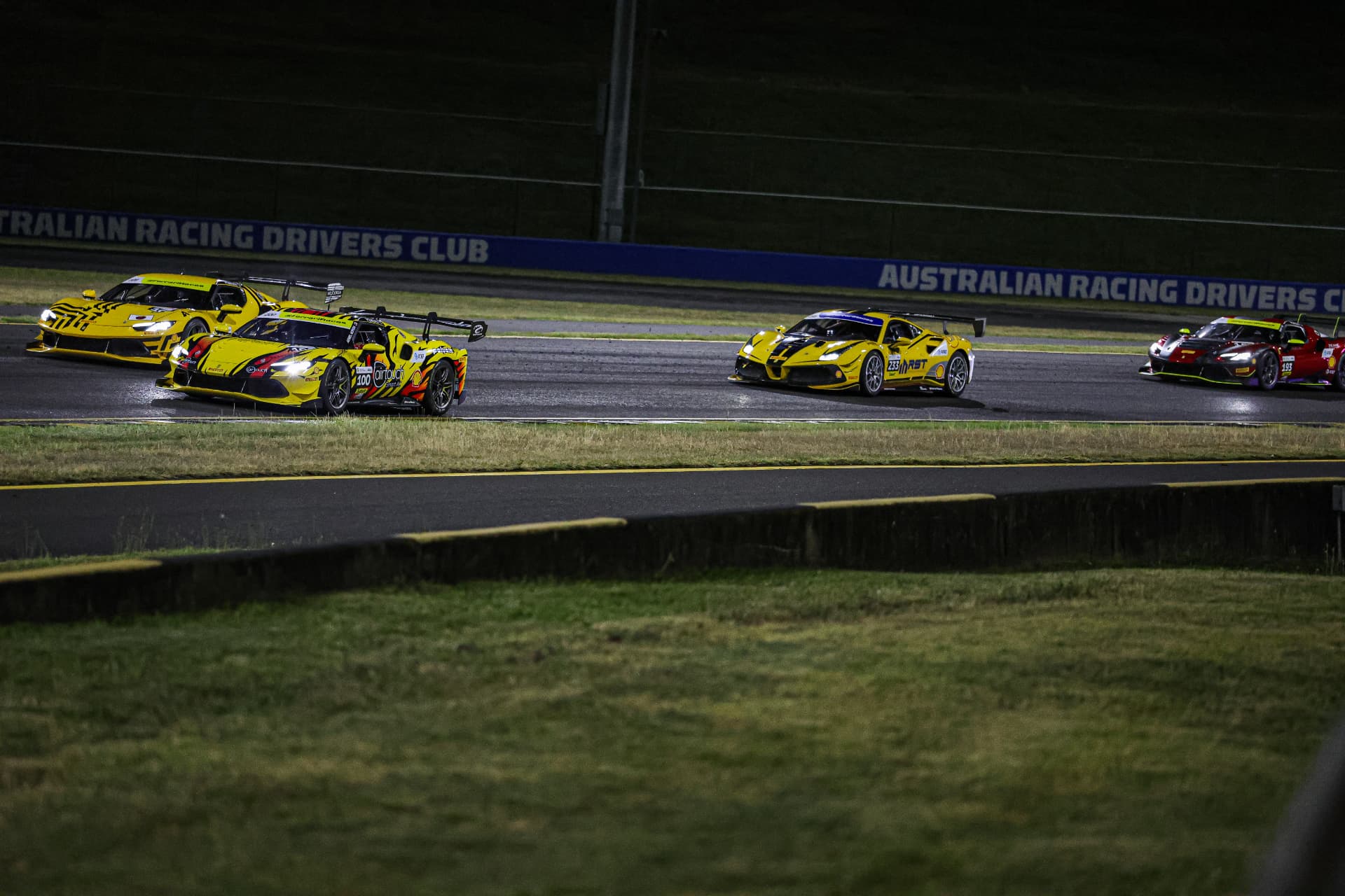 Pack of Ferrari Challenge cars racing past the Australian Racing Drivers Club wall