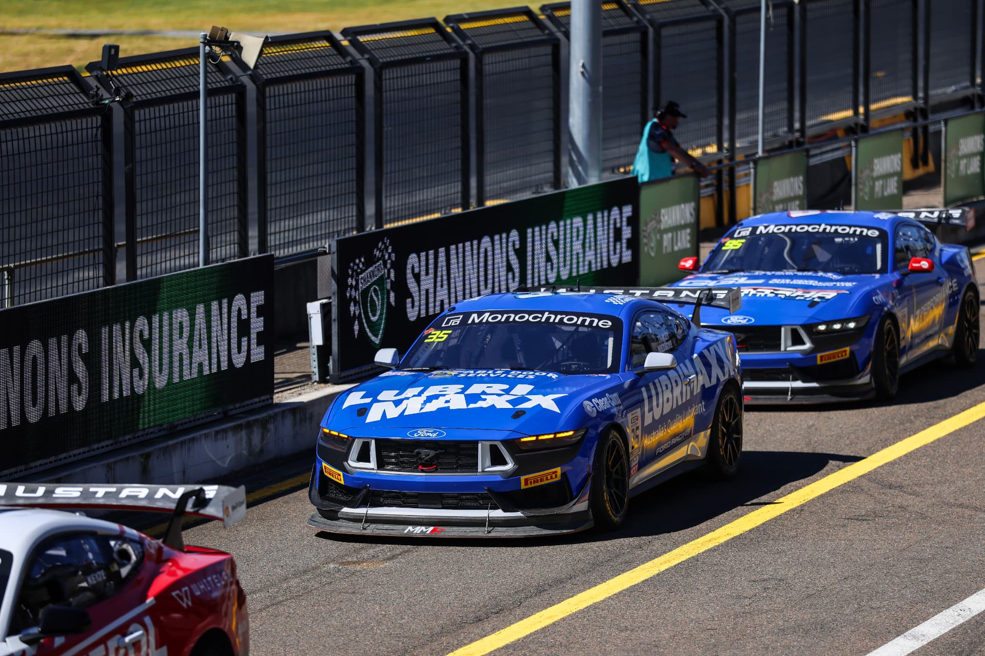 Two blue Mustang race cars leaving pit lane