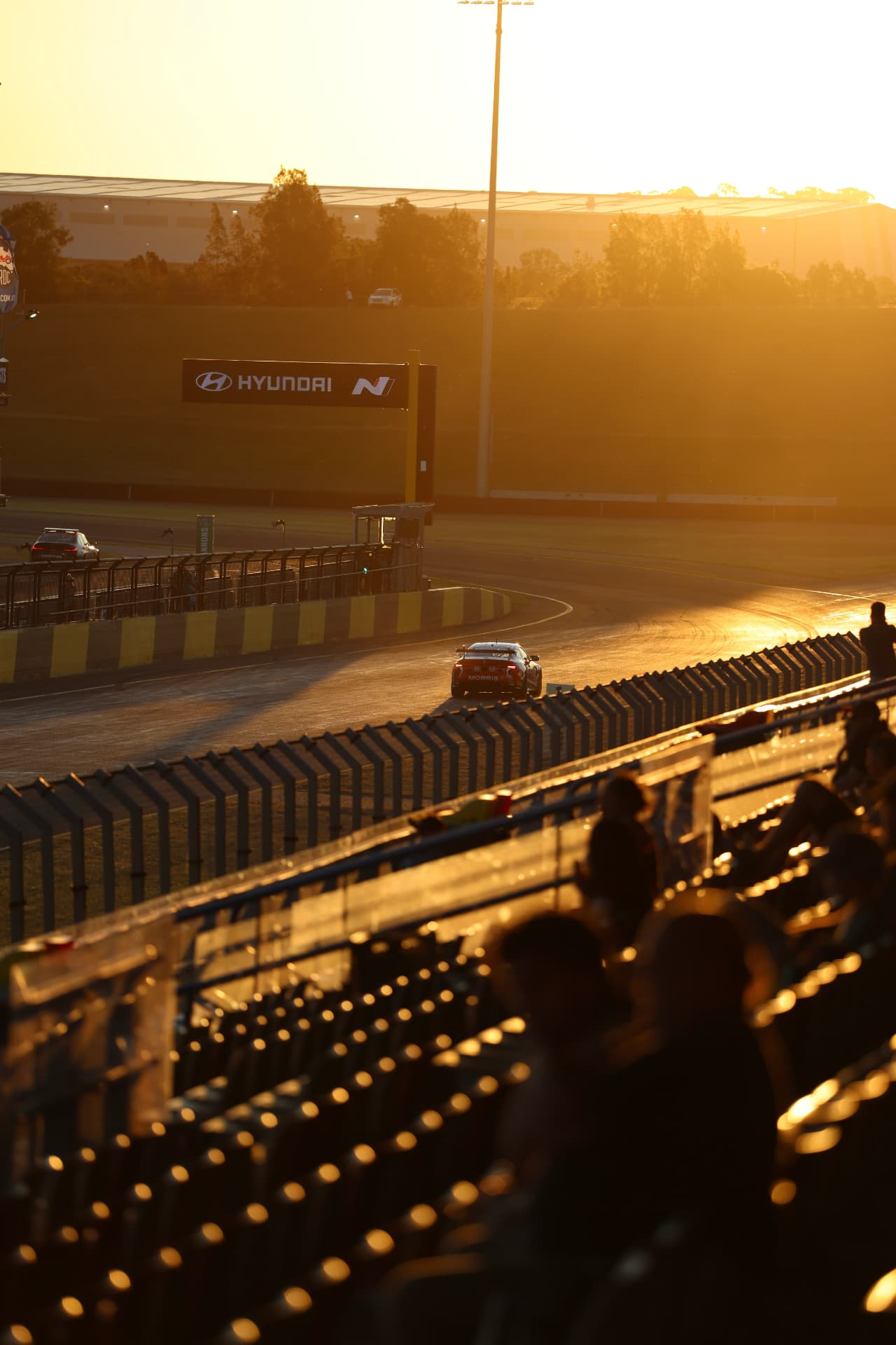 Race cars on the circuit at sunset, viewed from the grandstand