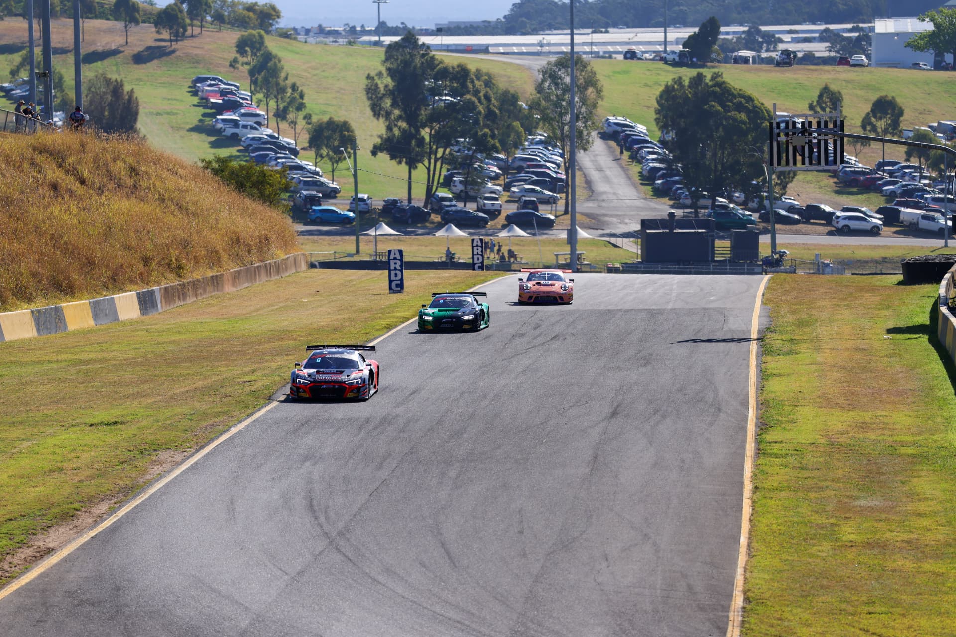 Four GT cars cresting the rise on a wide circuit view