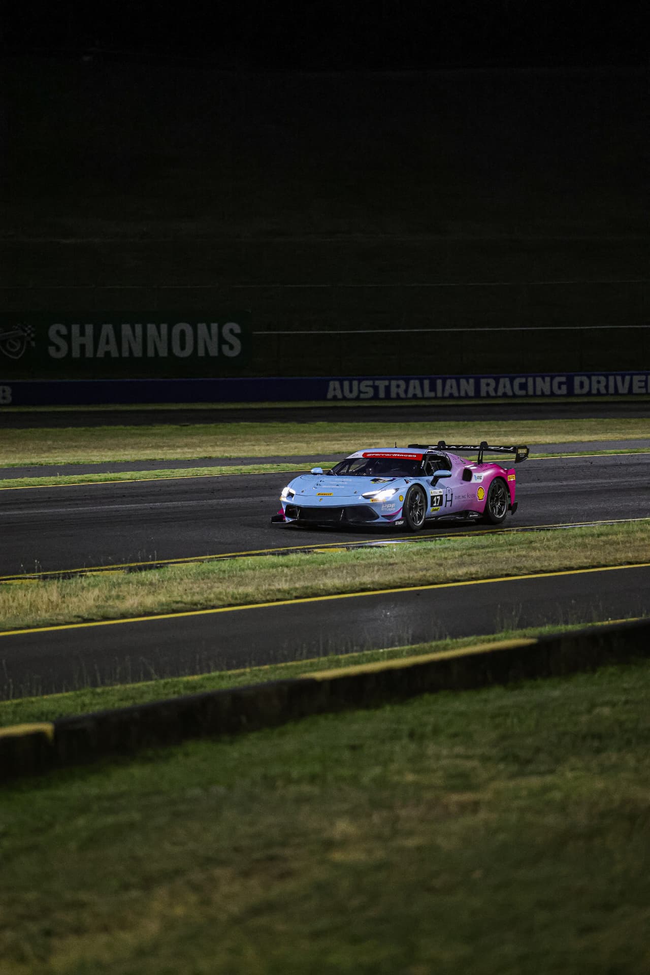 Blue and pink Ferrari #47 on track at night