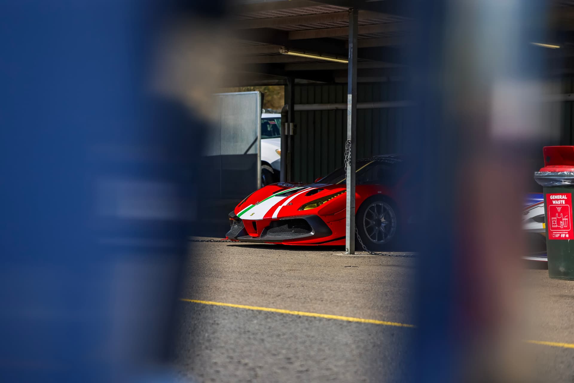 Red Ferrari Challenge car framed through a dark pit-garage opening