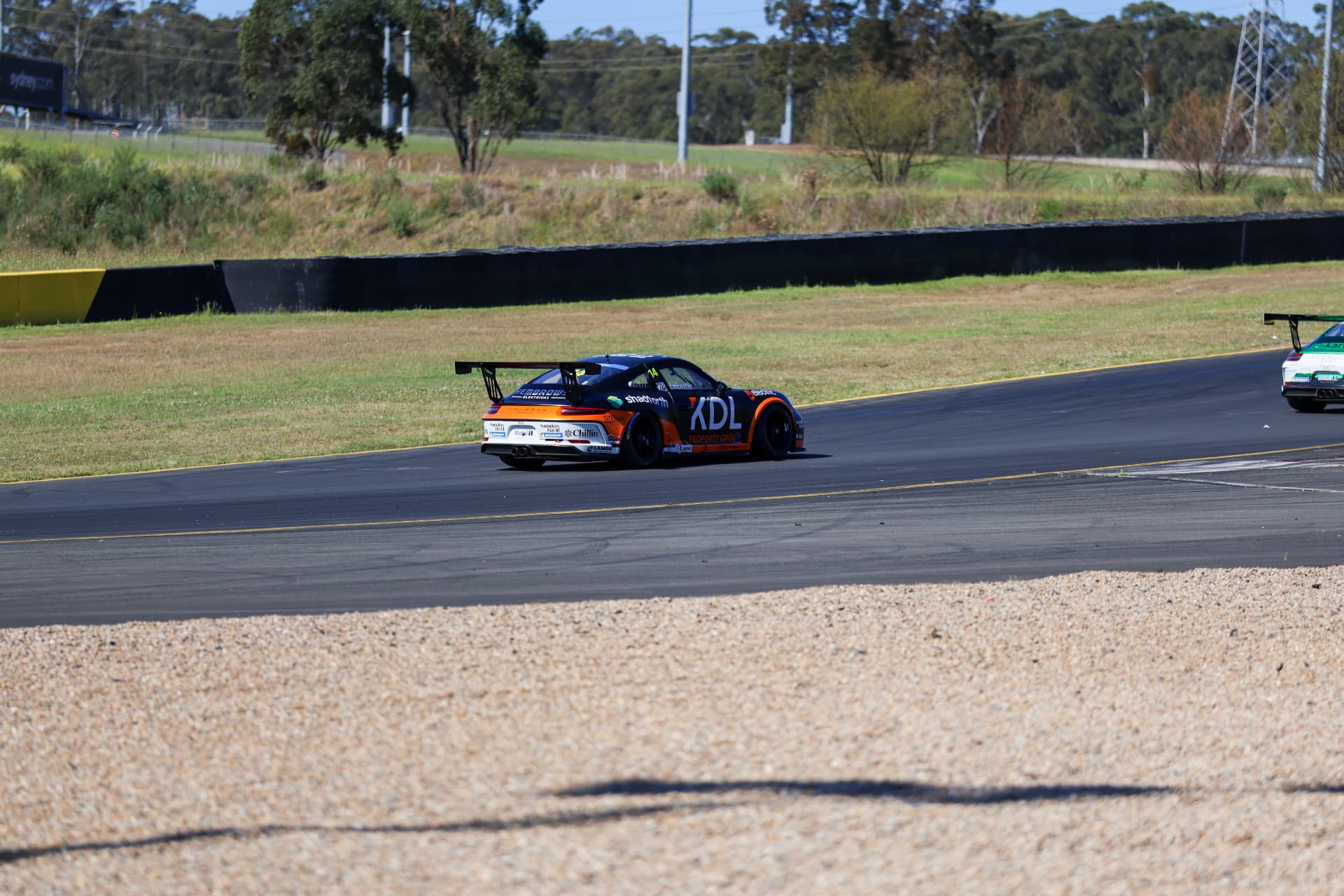 Blue and orange Porsche race car exiting a corner