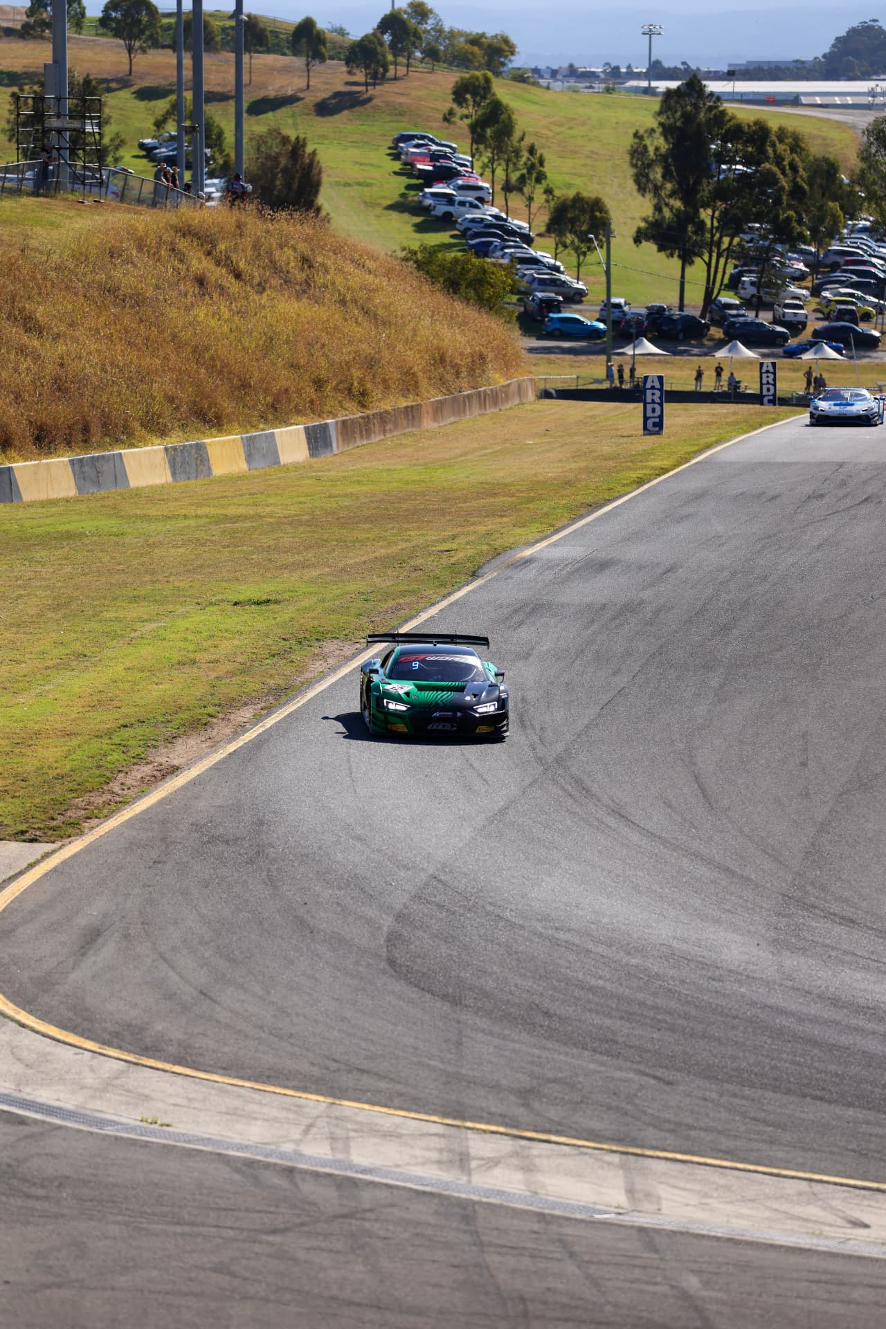 Green GT car climbing the circuit hill
