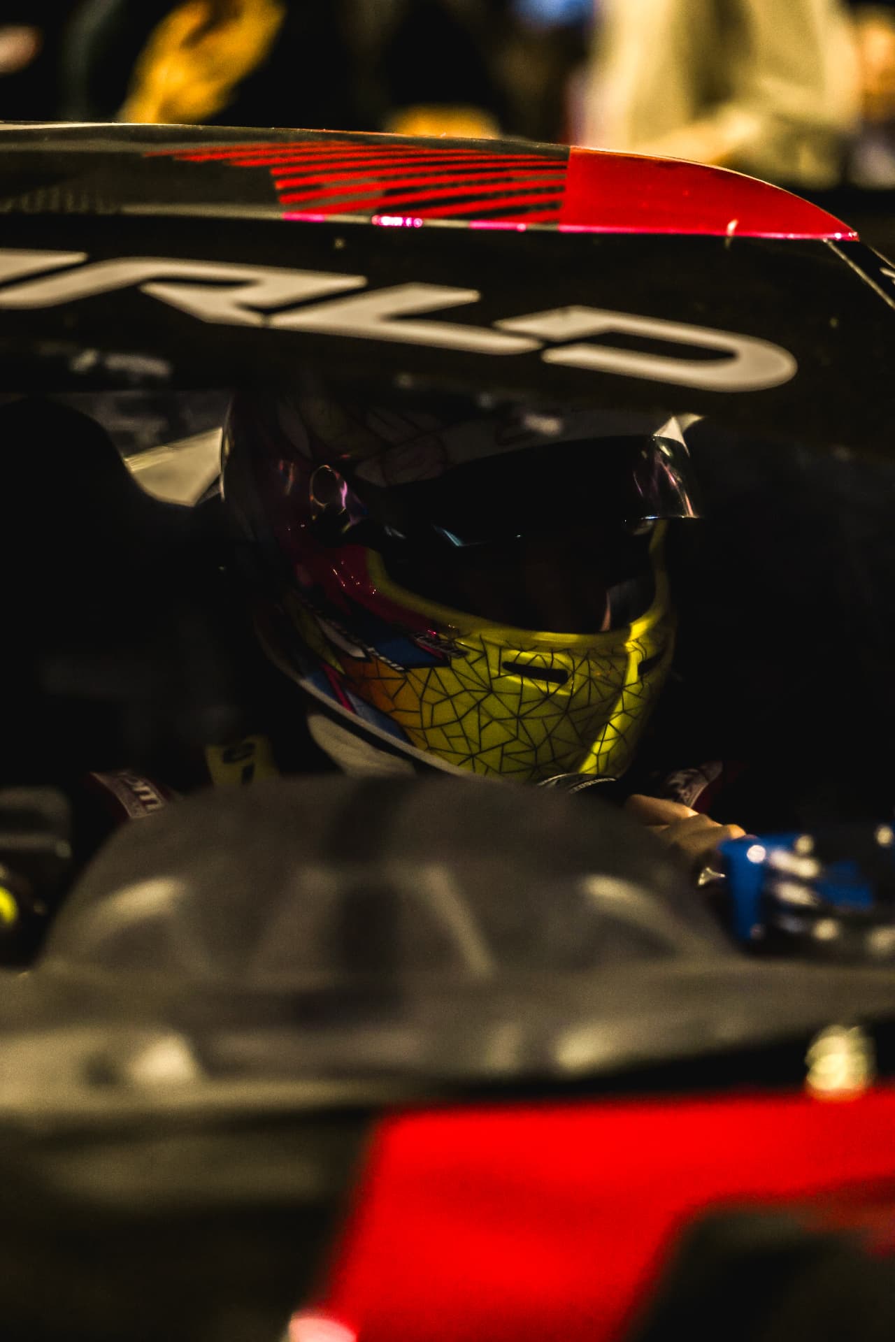 Helmeted driver waiting in the cockpit beneath a rear wing