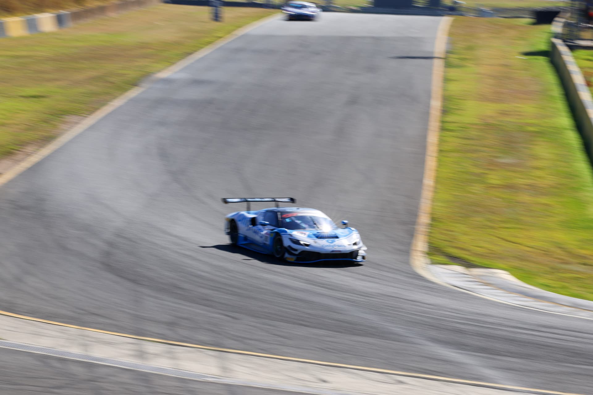 Blue Lamborghini GT car panned through a downhill bend