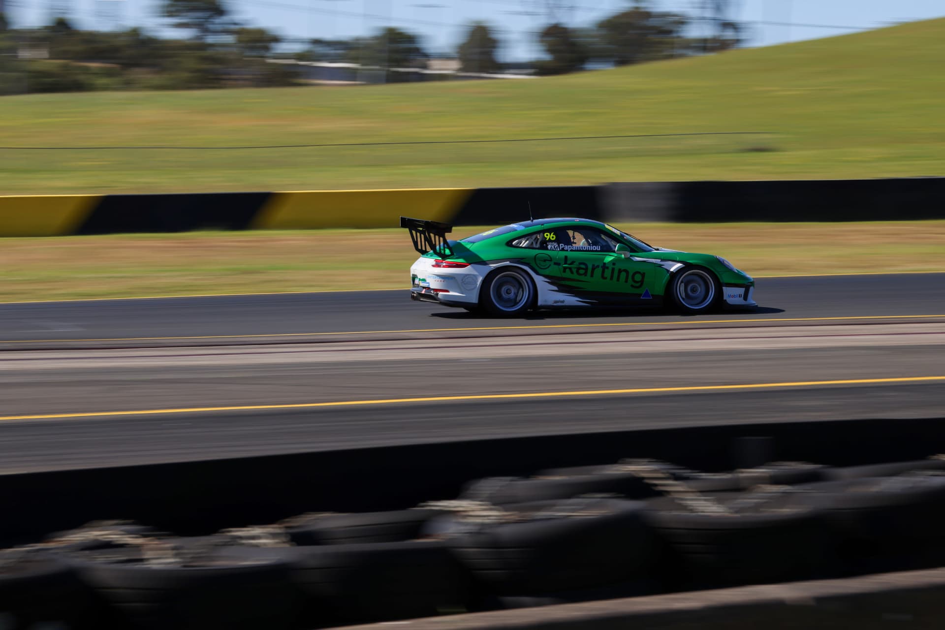 Green Porsche 911 GT3 #96 panned at speed along the circuit