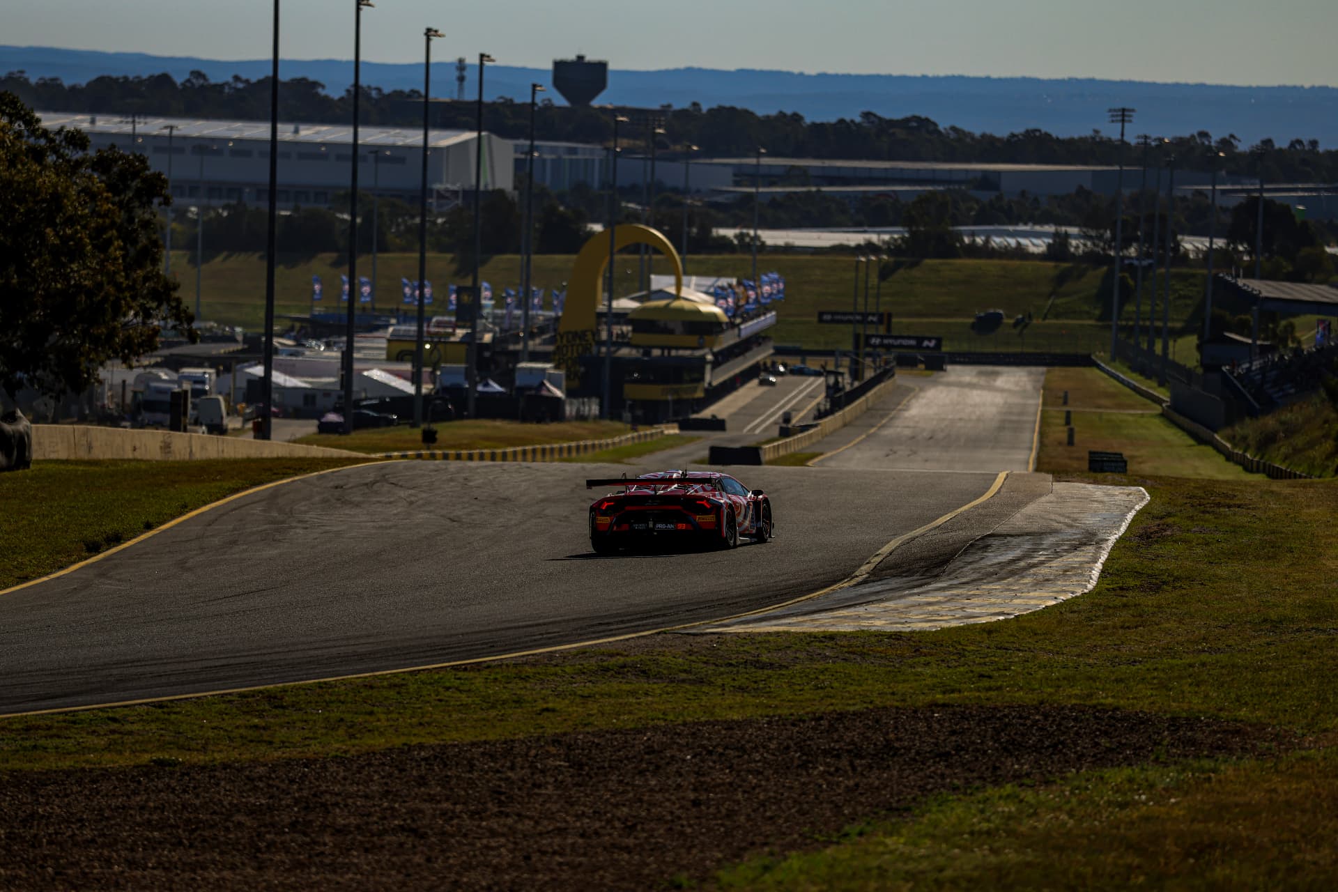 Red Lamborghini GT car heading down a long circuit descent