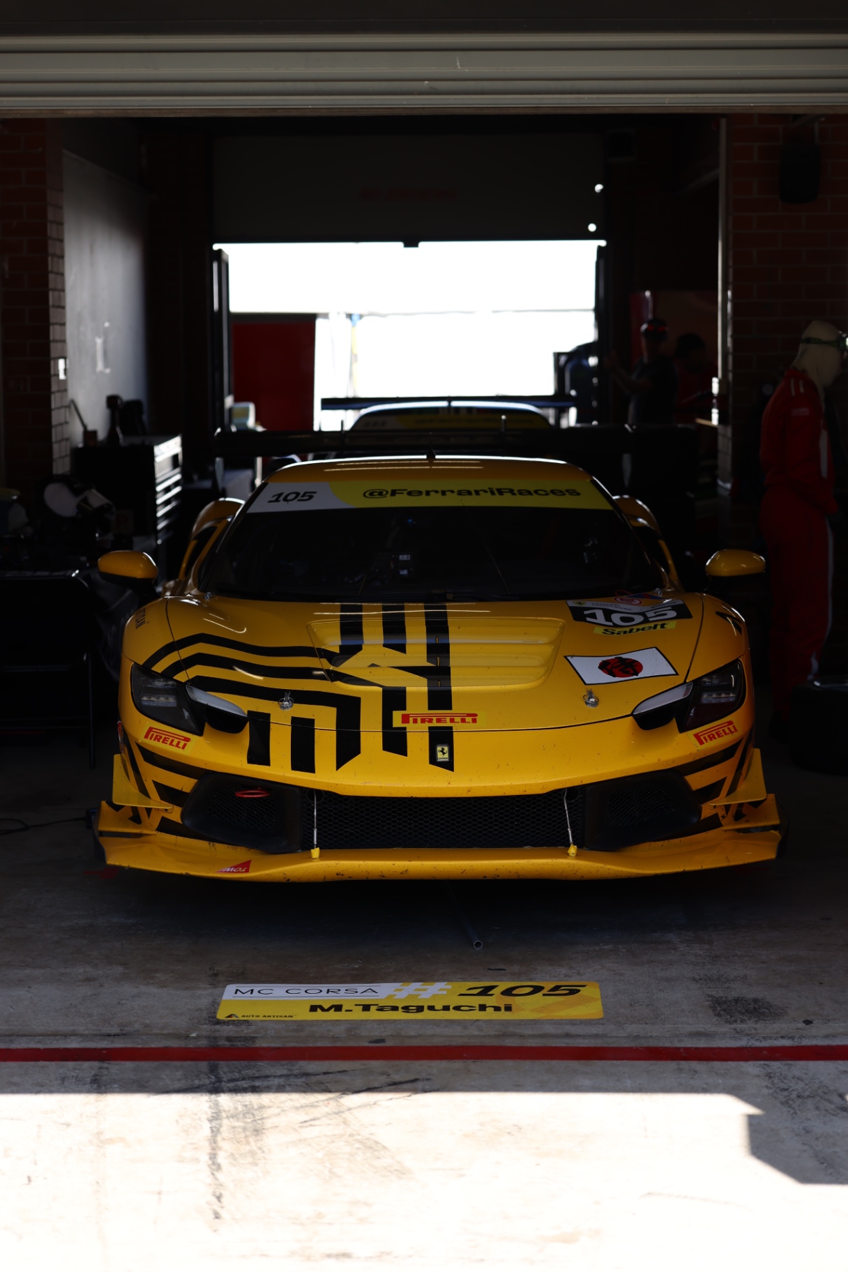 Yellow Ferrari 488 Challenge waiting in a dark pit garage
