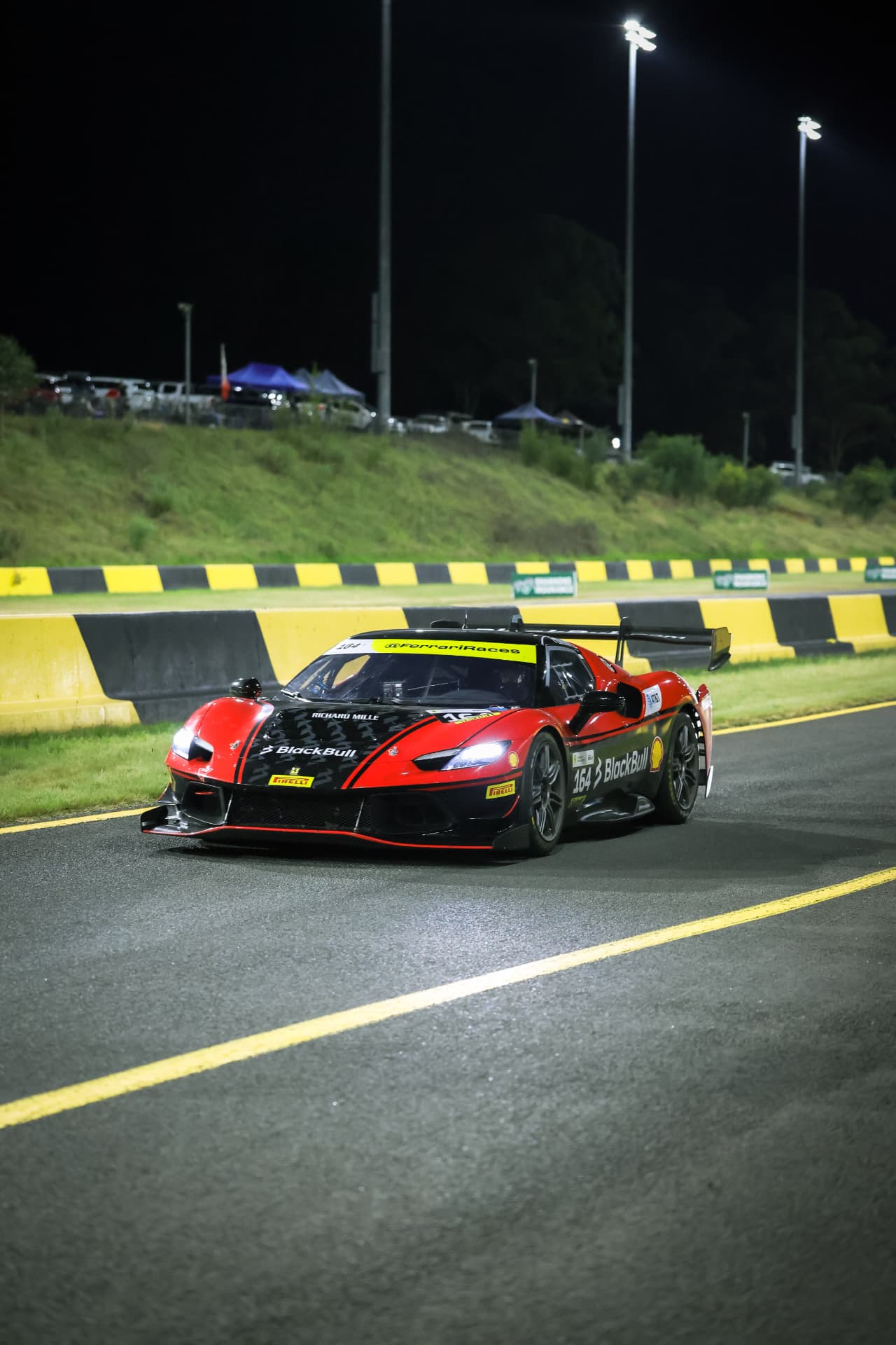 Red and black Ferrari GT car on the circuit at night