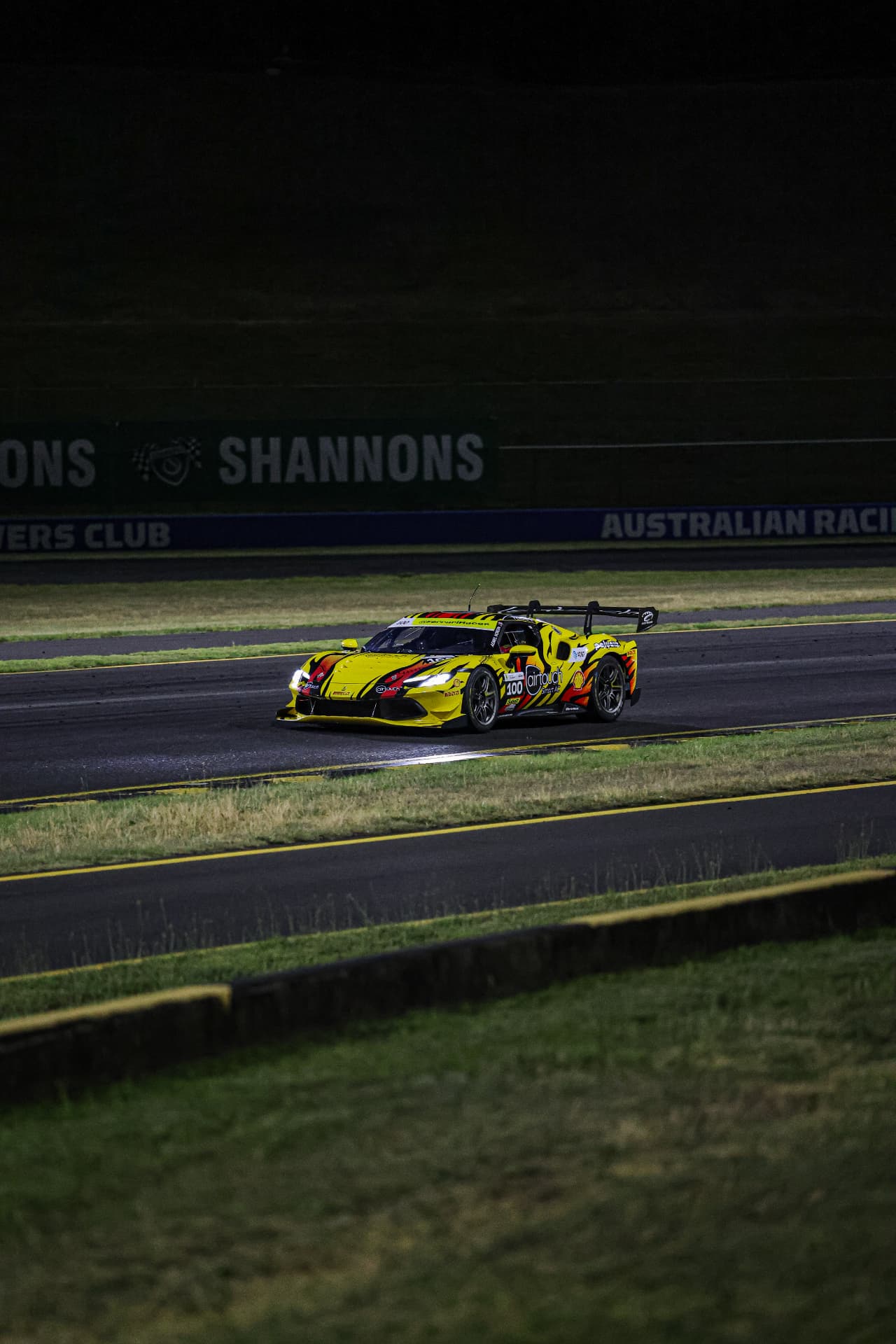 Yellow Ferrari #100 on track at night